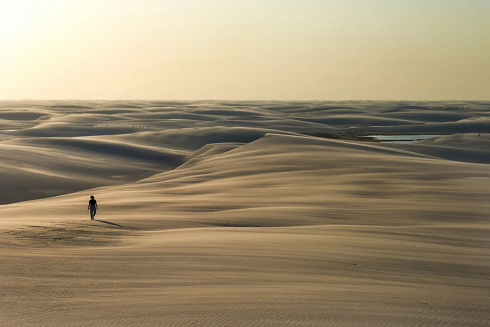 Pessoa caminhando sozinha entre as dunas dos Lençóis Maranhenses