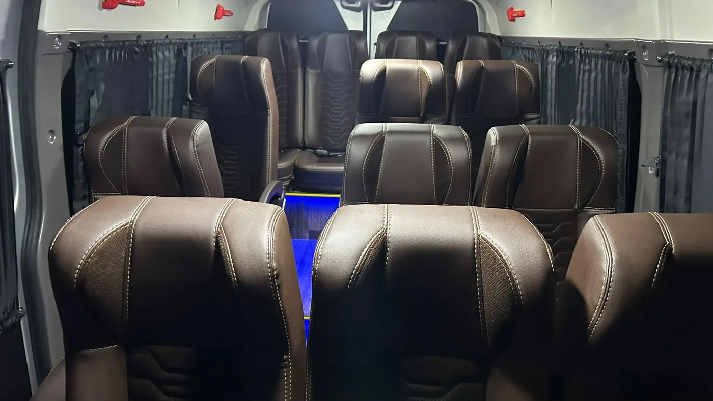 Interior da van com fileiras de poltronas para o grupo